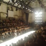 Model walking a fashion week catwalk before a live audience