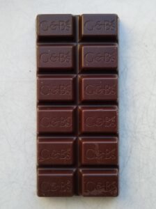 Dark chocolate bar unwrapped on a plain background
