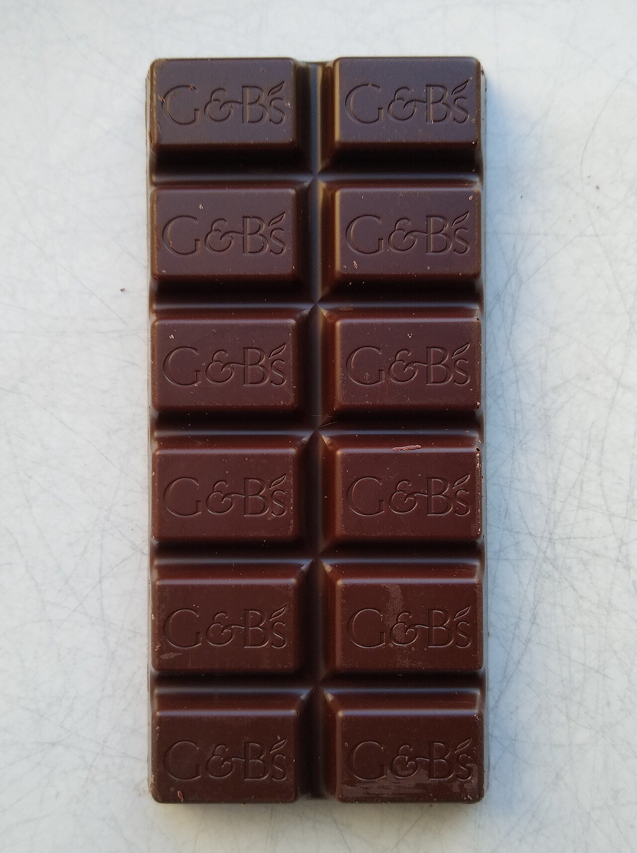 Dark chocolate bar unwrapped on a plain background