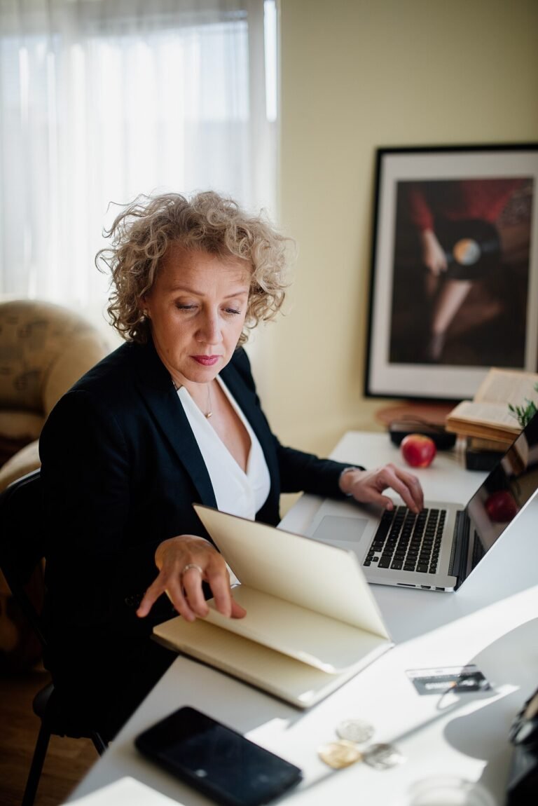 Professional woman working at a desk with laptop and documents in a bright office