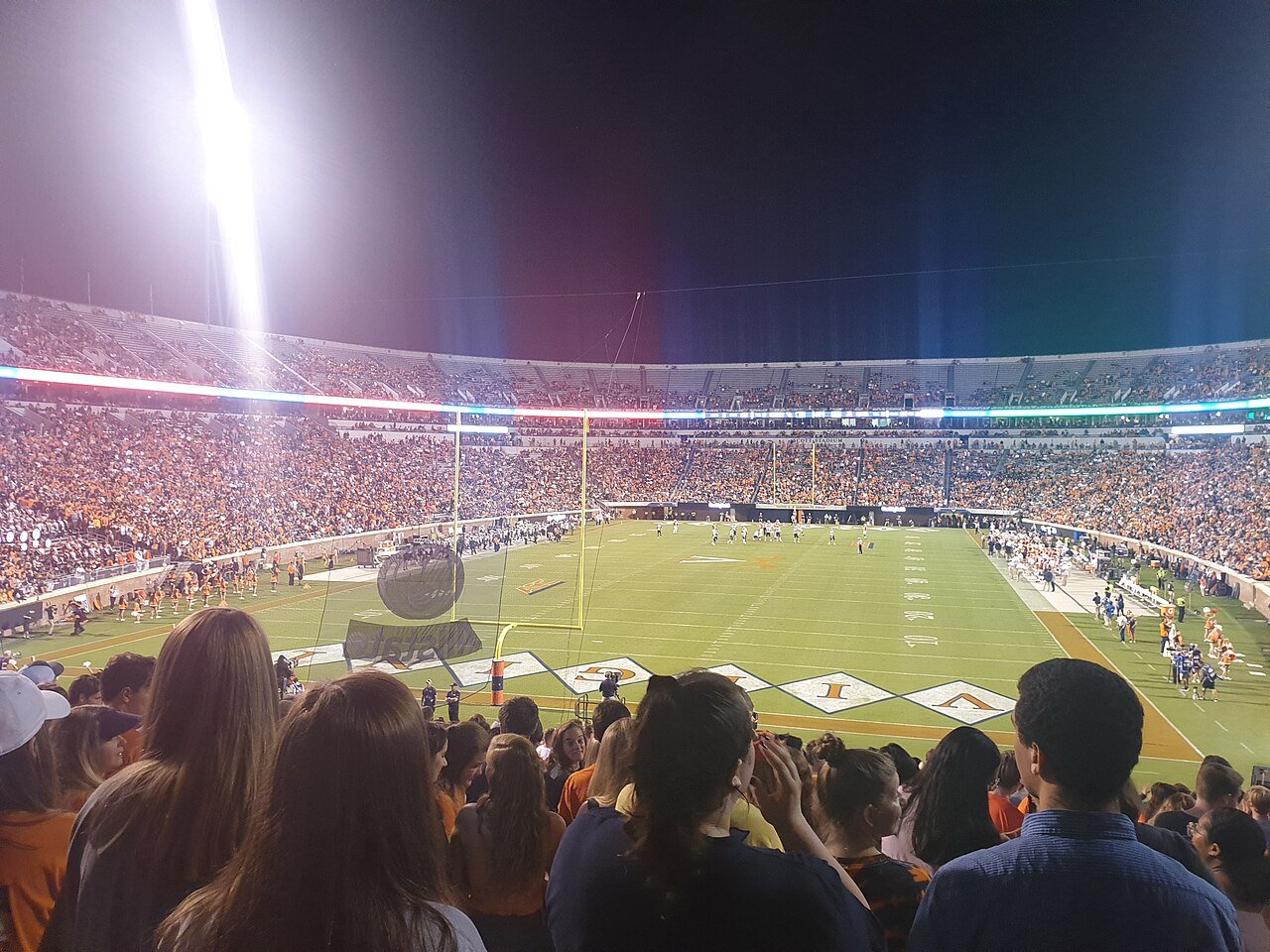 American football game in progress in a packed stadium